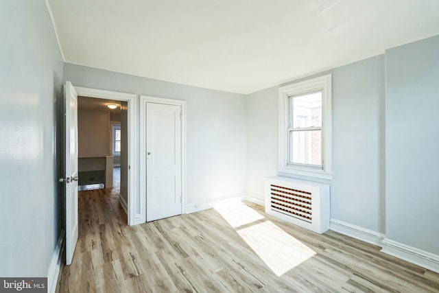 unfurnished room featuring heating unit, baseboards, and wood finished floors