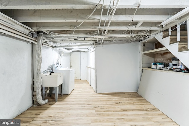 unfinished below grade area with light wood-style floors, washer and dryer, and a sink