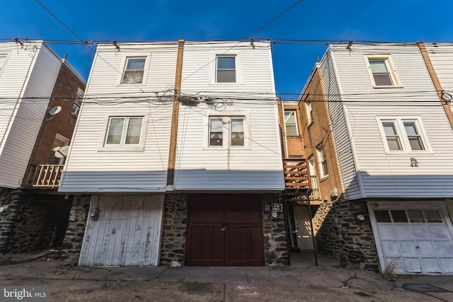 back of house featuring stone siding and an attached garage