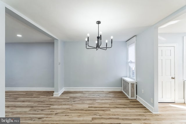 unfurnished dining area with light wood-type flooring, visible vents, a notable chandelier, and baseboards