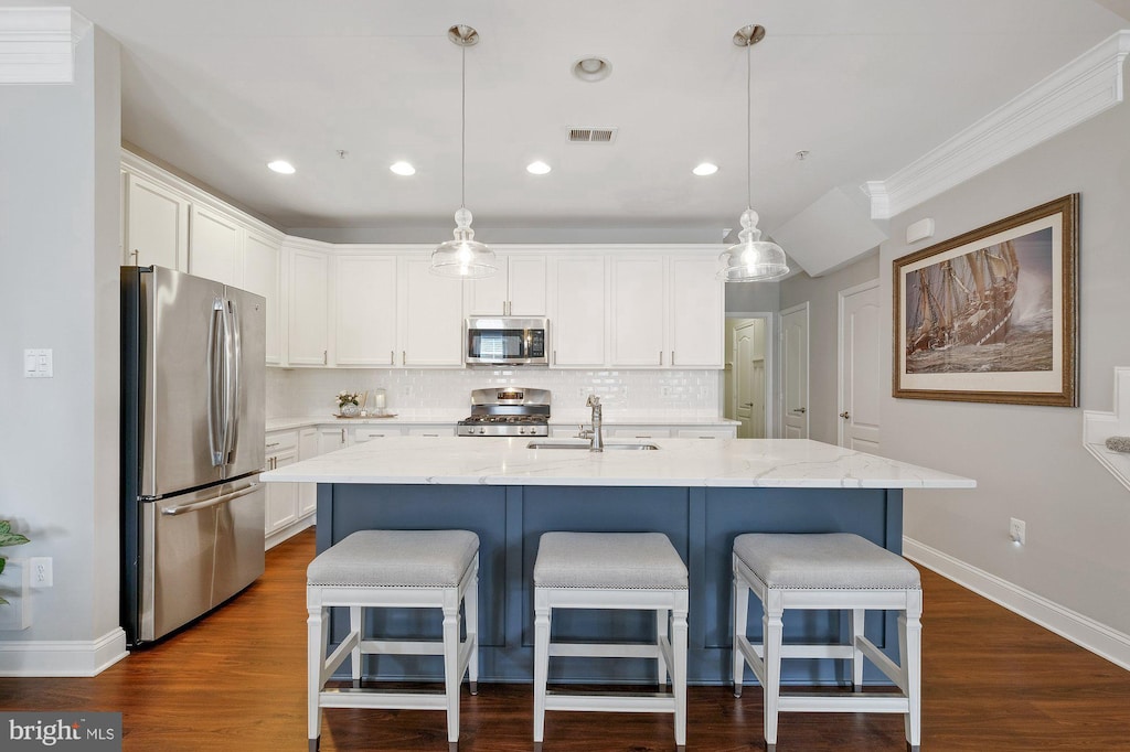 kitchen featuring stainless steel appliances, tasteful backsplash, visible vents, white cabinets, and a kitchen breakfast bar