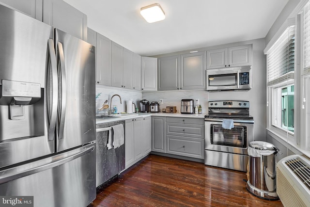 kitchen featuring dark wood finished floors, light countertops, gray cabinetry, appliances with stainless steel finishes, and a sink