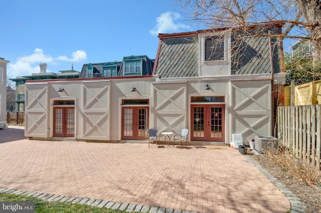 exterior space with french doors, mansard roof, and fence