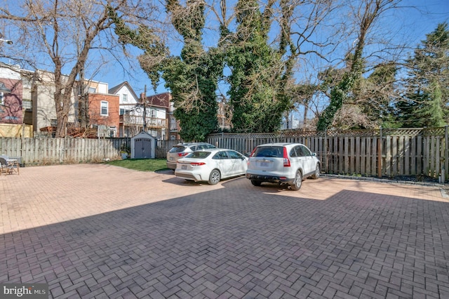 uncovered parking lot featuring a storage unit and fence private yard