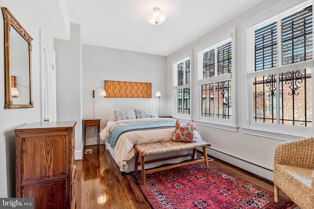 bedroom with baseboards, baseboard heating, and wood finished floors