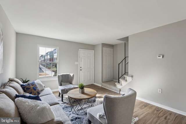 living area featuring wood finished floors, baseboards, and stairs