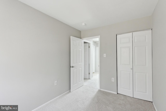 unfurnished bedroom with a closet, carpet, and baseboards