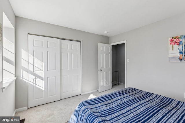 carpeted bedroom with a closet and baseboards