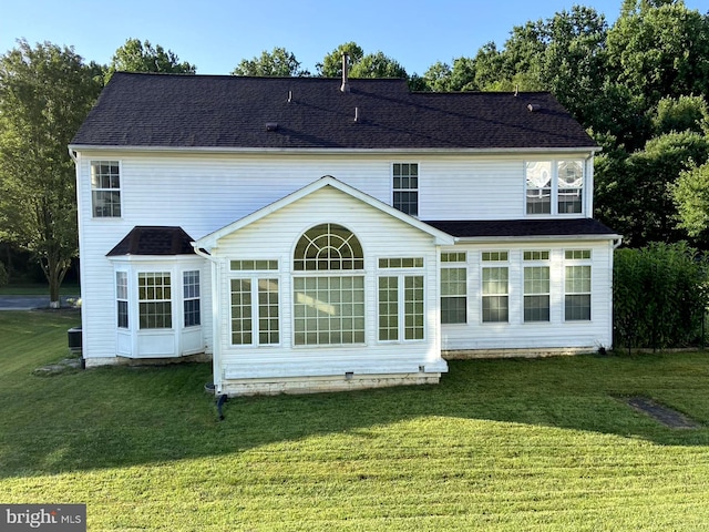 rear view of house featuring a yard and a shingled roof