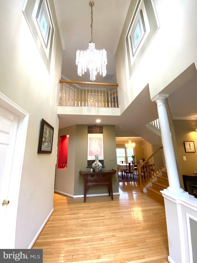 entryway featuring ornate columns, a notable chandelier, and wood finished floors