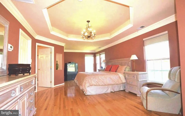 bedroom with light wood-style flooring, visible vents, an inviting chandelier, a raised ceiling, and crown molding