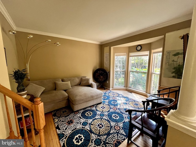 living room featuring decorative columns, hardwood / wood-style flooring, and crown molding