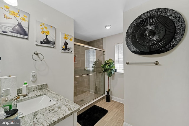 full bathroom featuring a stall shower, wood finish floors, vanity, and baseboards