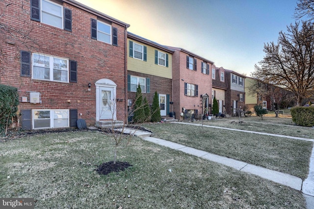 view of front of property with brick siding, a residential view, entry steps, and a yard