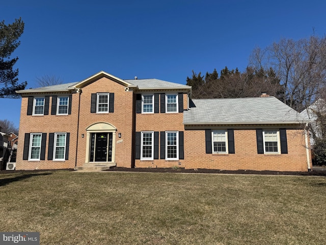 colonial house featuring brick siding and a front lawn