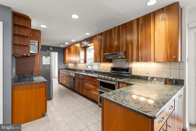 kitchen featuring brown cabinetry, stainless steel appliances, under cabinet range hood, open shelves, and a sink