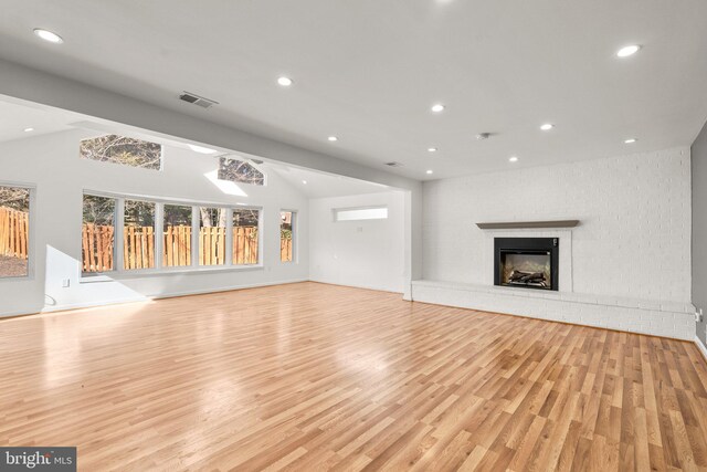 unfurnished living room with lofted ceiling, recessed lighting, visible vents, light wood-type flooring, and a brick fireplace