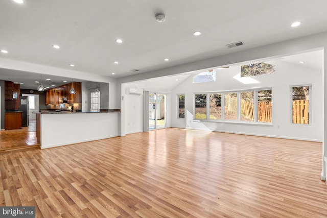 unfurnished living room with baseboards, visible vents, vaulted ceiling, light wood-style floors, and recessed lighting