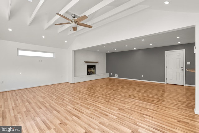 unfurnished living room featuring light wood-type flooring, a fireplace, a ceiling fan, and beamed ceiling