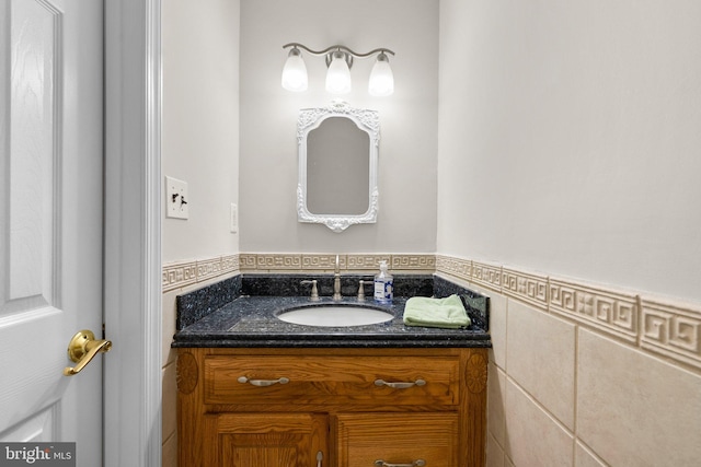 bathroom with a wainscoted wall, tile walls, and vanity