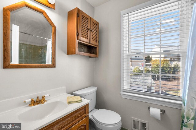 bathroom with toilet, vanity, visible vents, and a shower with curtain