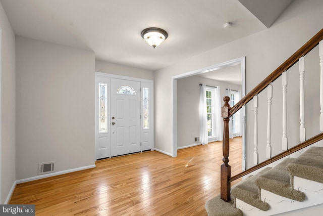 foyer entrance featuring light wood-type flooring, visible vents, stairway, and baseboards