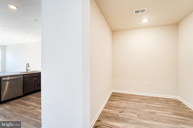 corridor featuring baseboards, visible vents, light wood-style flooring, a sink, and recessed lighting