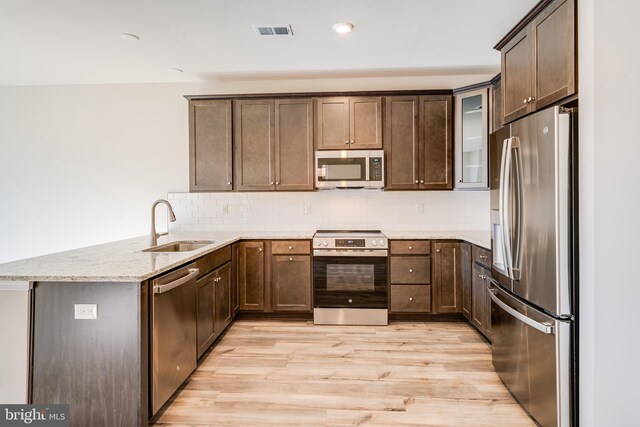 kitchen with stainless steel appliances, visible vents, light wood-style floors, a sink, and a peninsula
