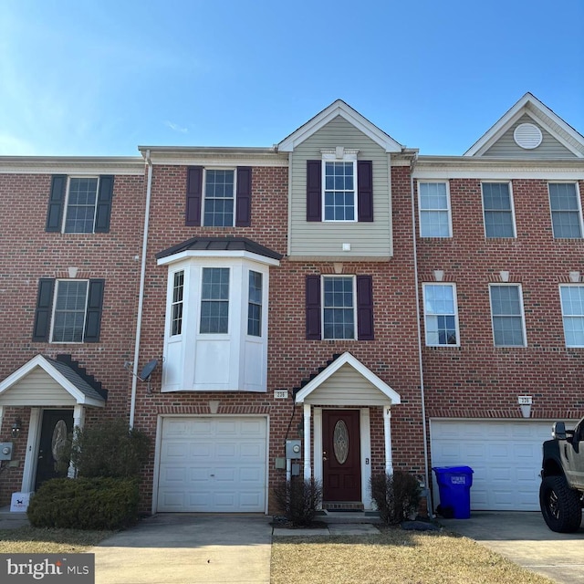 townhome / multi-family property with driveway, brick siding, and an attached garage