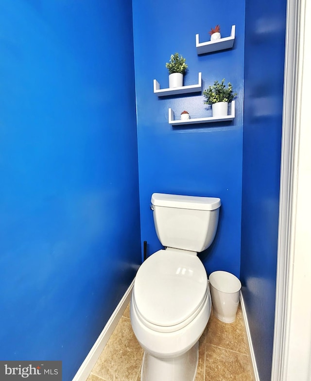 bathroom with baseboards, toilet, and tile patterned flooring