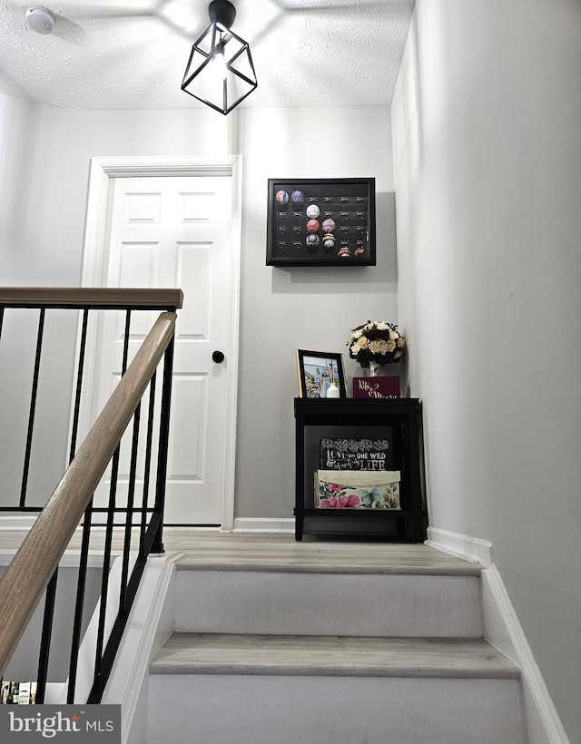 stairs featuring baseboards and a textured ceiling