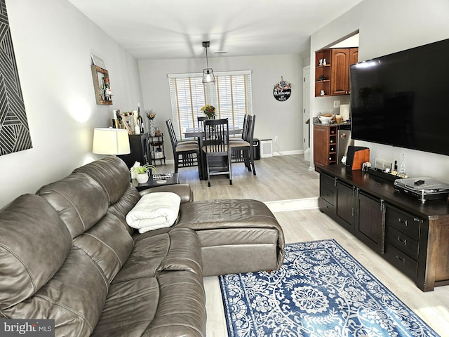 living area featuring baseboards and light wood finished floors