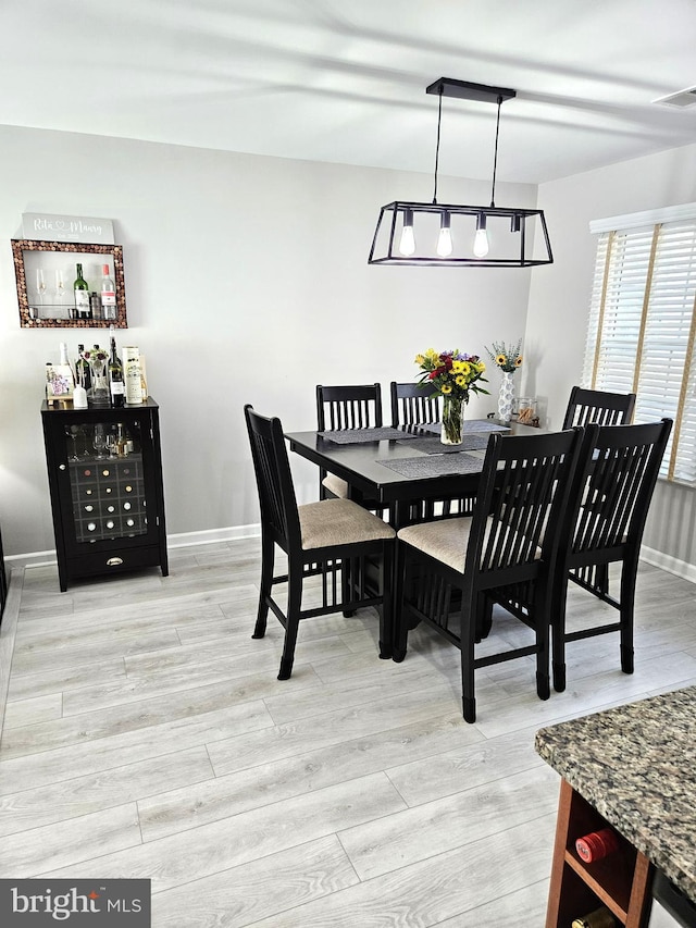 dining room with visible vents, baseboards, and light wood finished floors