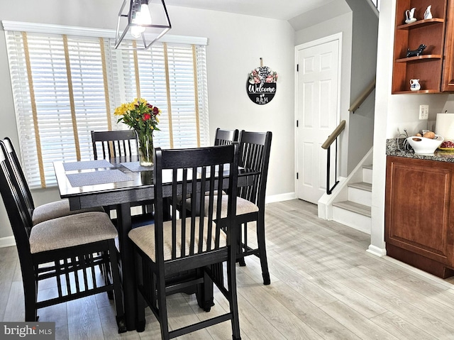 dining area featuring stairs, baseboards, and light wood finished floors