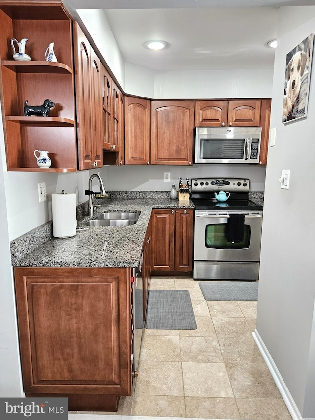 kitchen with a sink, stainless steel appliances, open shelves, and dark stone counters