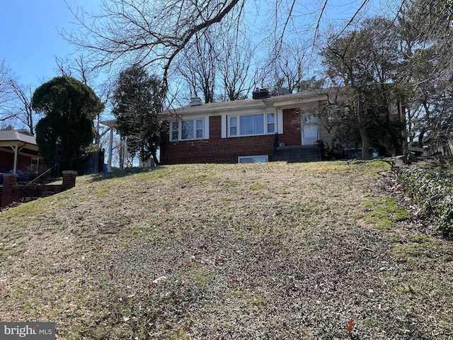 ranch-style home with a front yard, brick siding, and a chimney