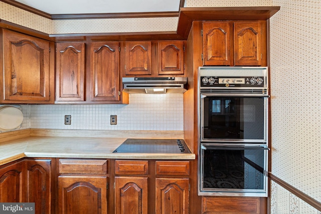 kitchen with black appliances, wallpapered walls, under cabinet range hood, and light countertops