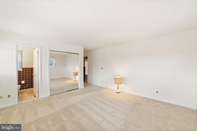 unfurnished bedroom featuring connected bathroom, a closet, and carpet flooring