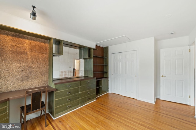 unfurnished bedroom featuring attic access, light wood-type flooring, a closet, and baseboards