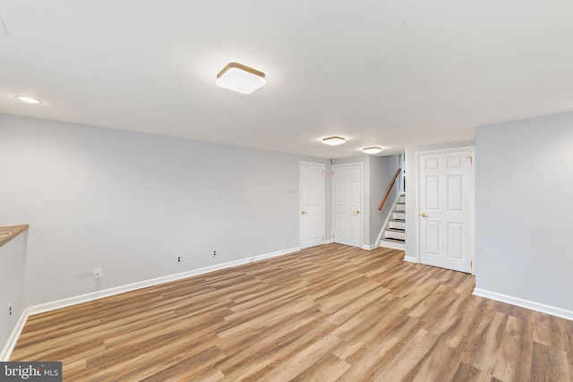 finished basement featuring light wood-style flooring, stairway, and baseboards