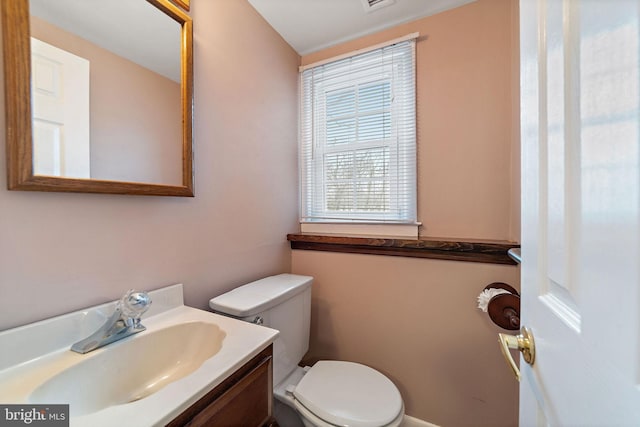 half bath featuring visible vents, vanity, and toilet