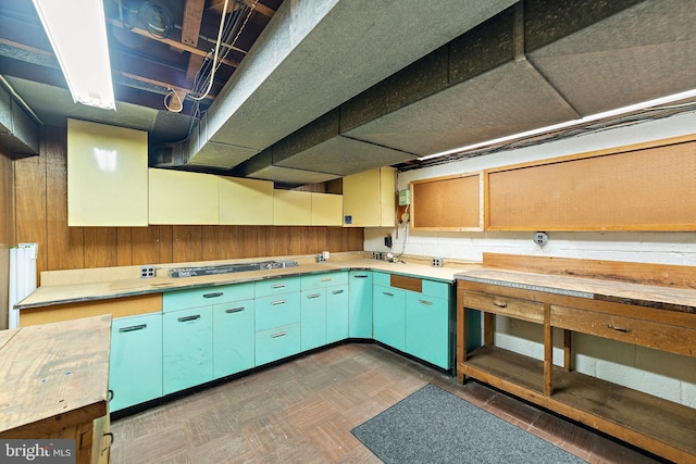 kitchen with dark floors, cooktop, light countertops, and wooden walls