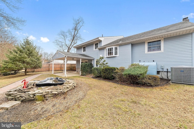 back of property featuring cooling unit, fence, a lawn, a chimney, and a patio area