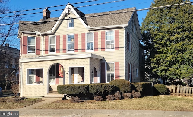 view of front of home featuring roof with shingles, a chimney, and fence