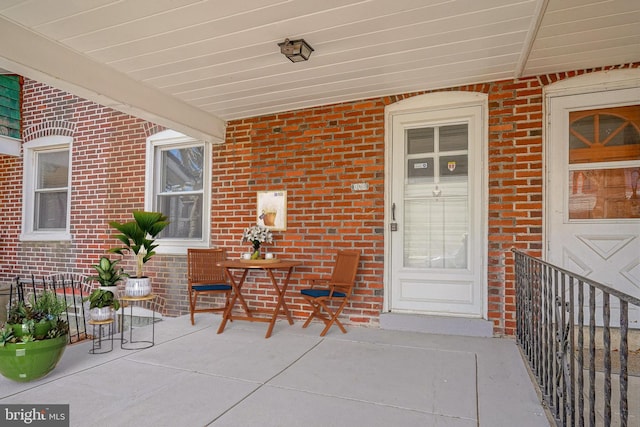 view of exterior entry featuring a porch and brick siding