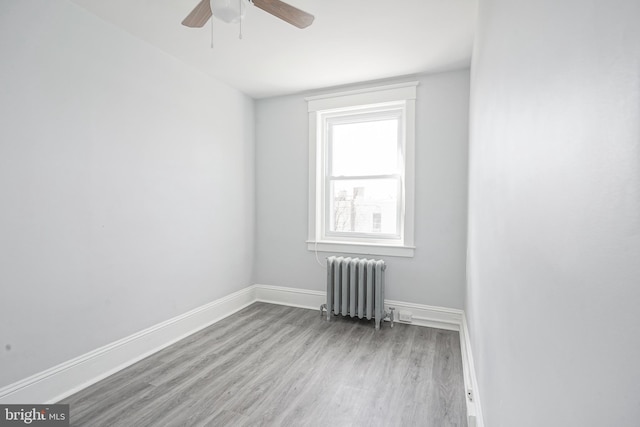 unfurnished room with ceiling fan, radiator heating unit, wood finished floors, and baseboards