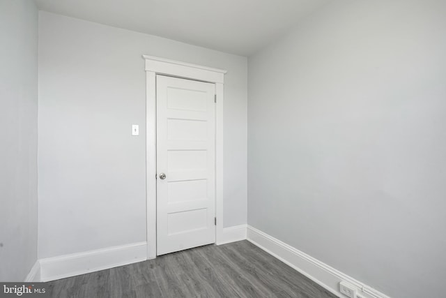 spare room with dark wood-type flooring and baseboards