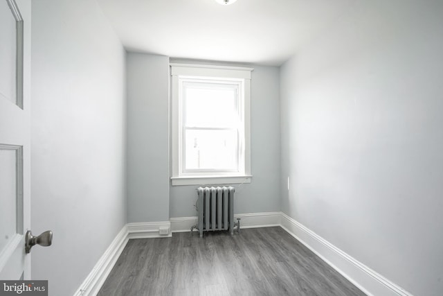 unfurnished room with radiator heating unit, baseboards, and wood finished floors