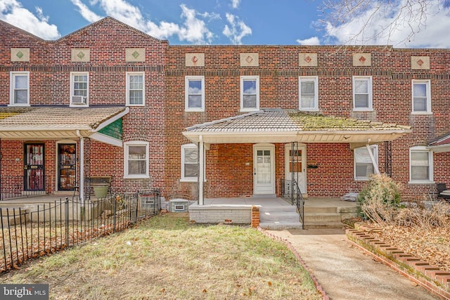 multi unit property with covered porch, brick siding, and fence