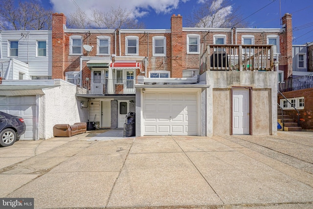 view of front facade with a garage, concrete driveway, brick siding, and a balcony